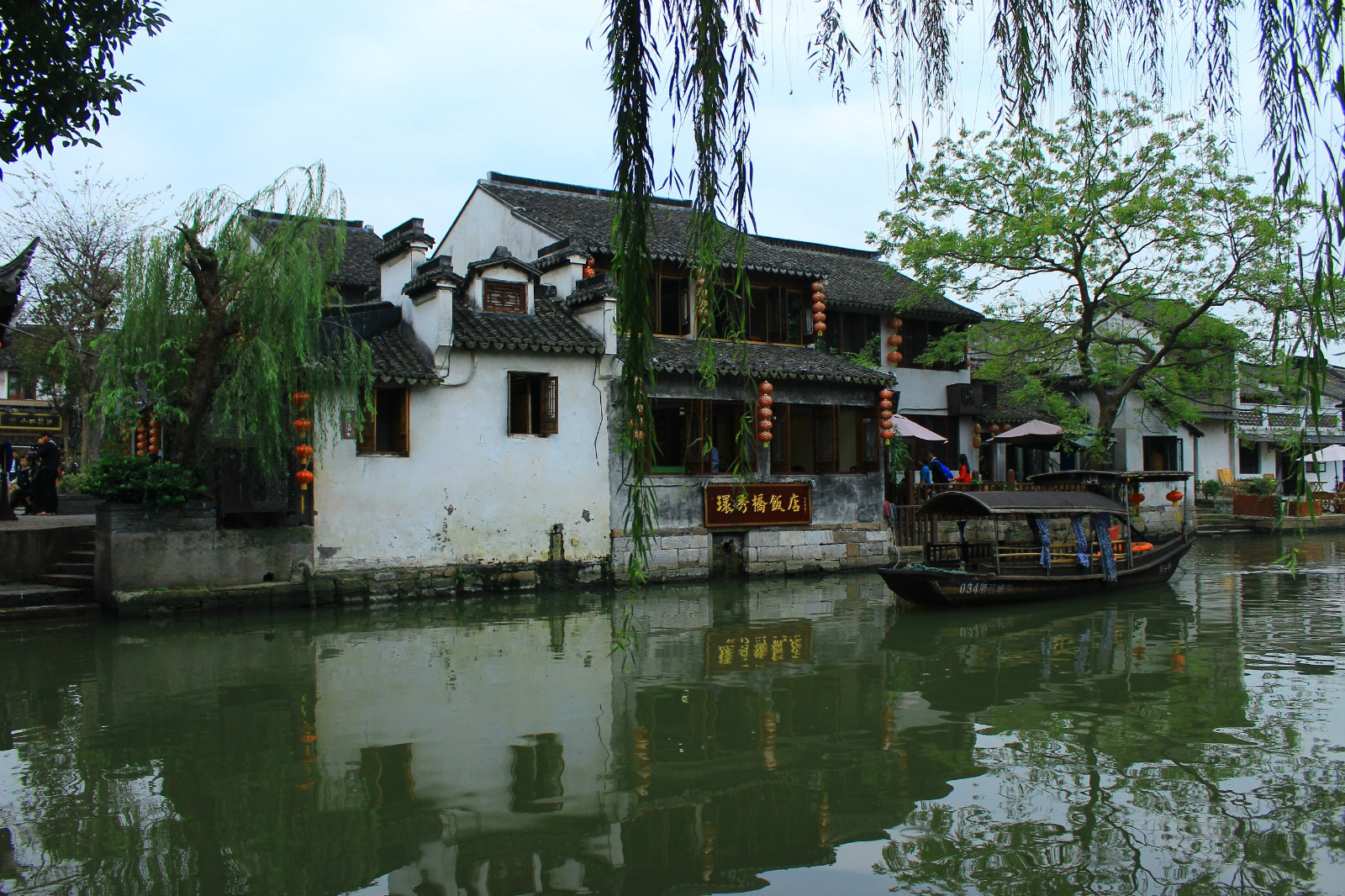 是粉墙黛瓦的邻水人家一边是烟雨长廊外的茵茵绿树好一派江南水乡风情