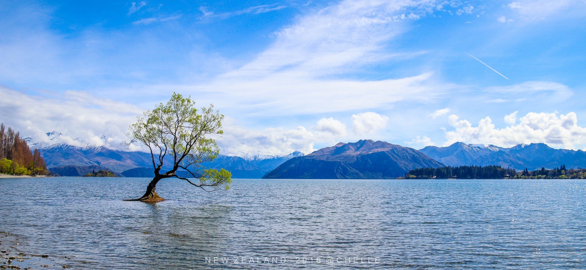 初晨的阳光洒向湖面宁静的湖水倒映着彩色的小镇和远处的雪山平静的