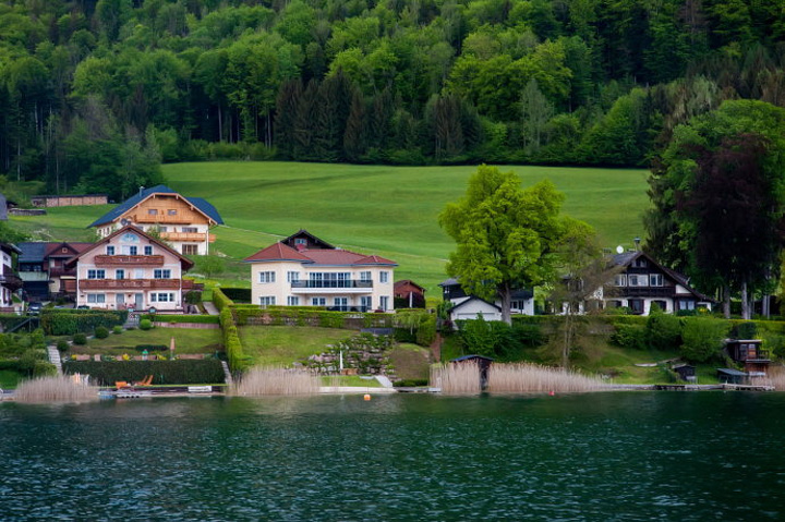 一边是山坡上墨绿色的密林一边是湛蓝的湖水景色非常美丽湖光山色异常