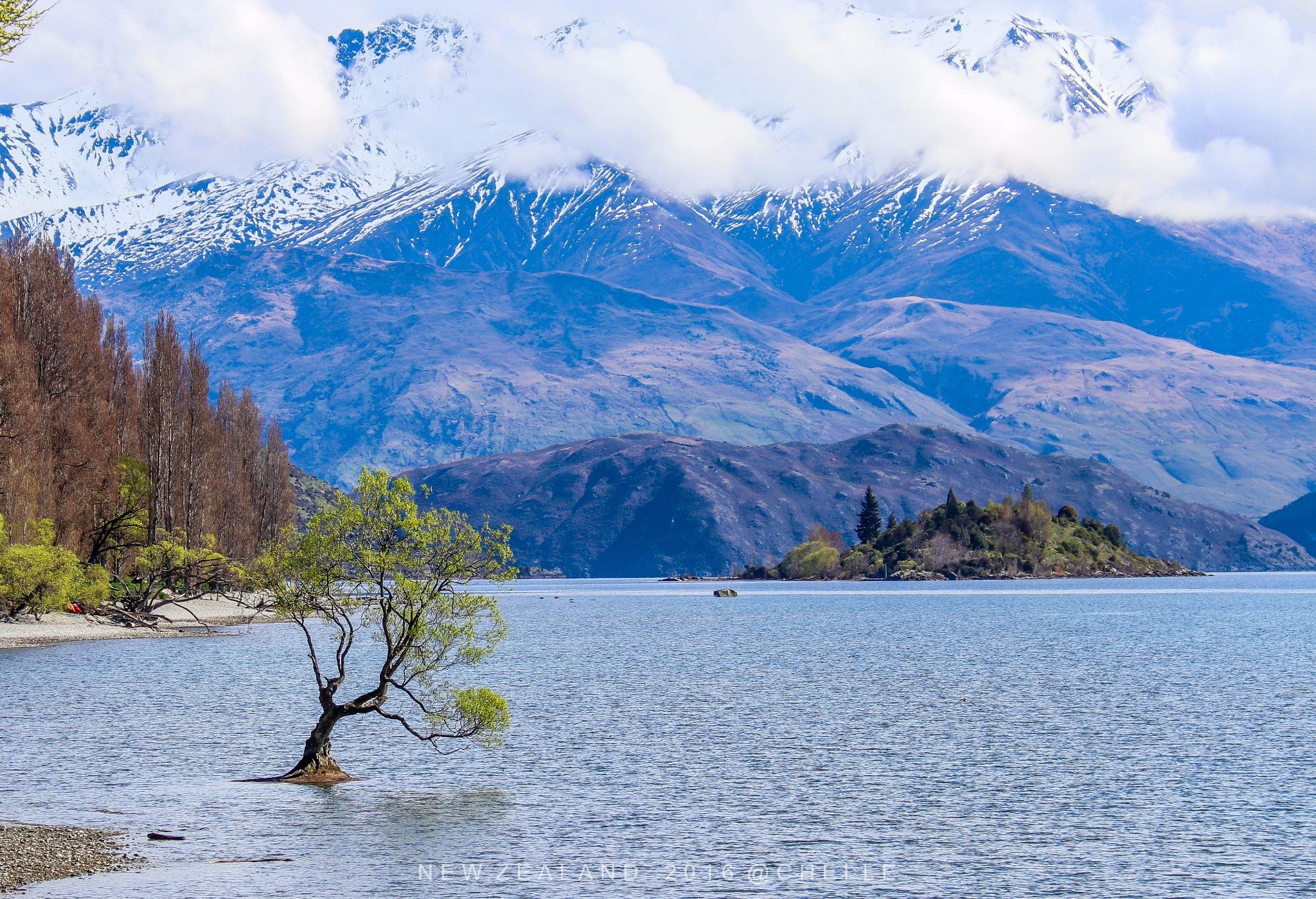 初晨的阳光洒向湖面宁静的湖水倒映着彩色的小镇和远处的雪山平静的