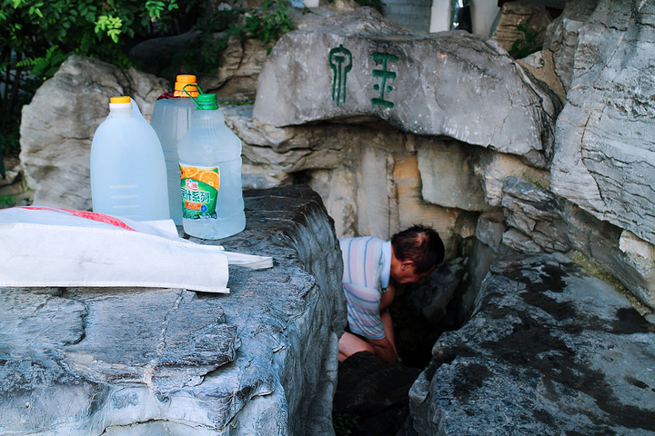 在公园里会看到很多市民拿着几个大瓶子接泉水他们告