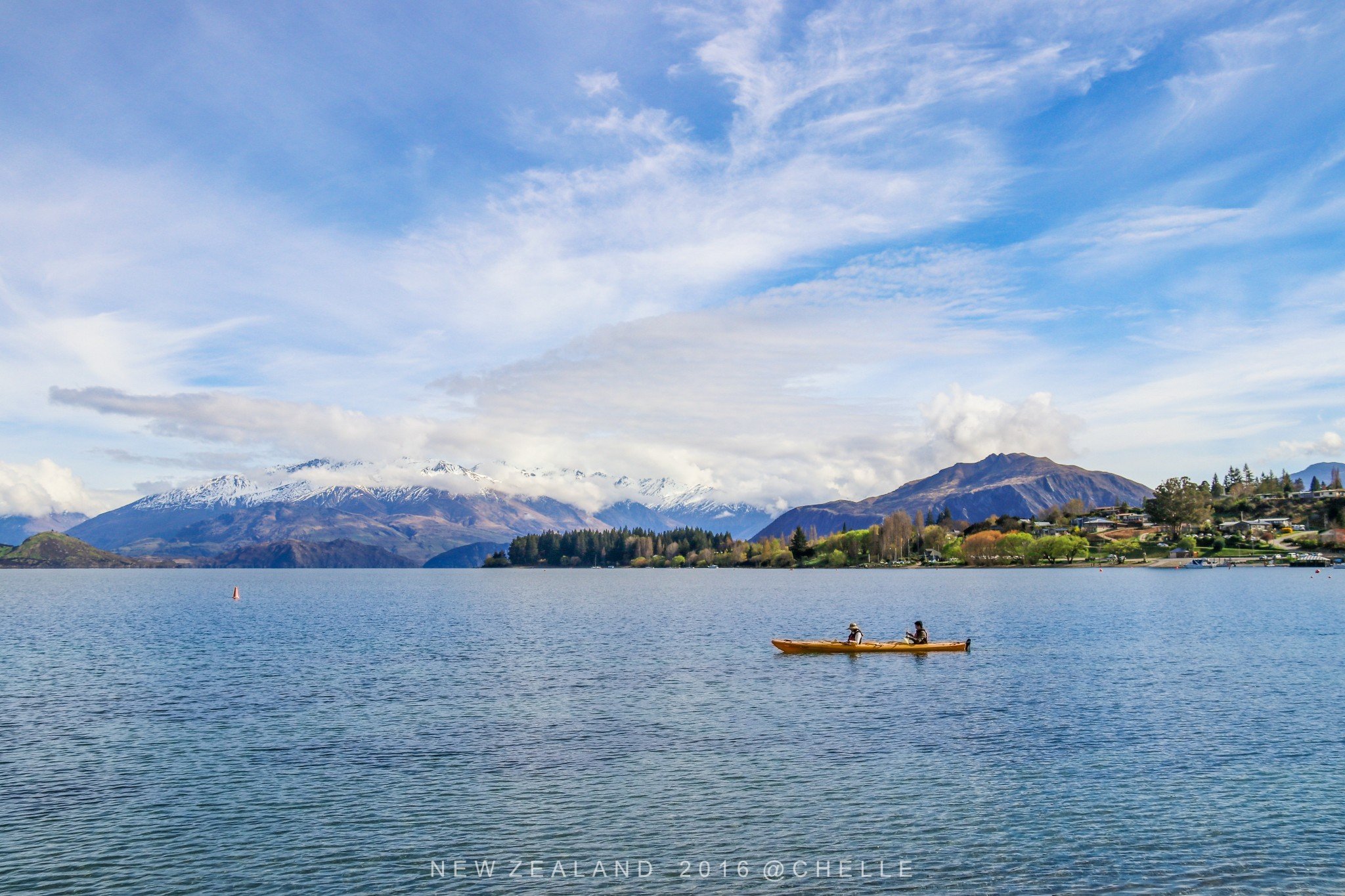 初晨的阳光洒向湖面宁静的湖水倒映着彩色的小镇和远处的雪山平静的