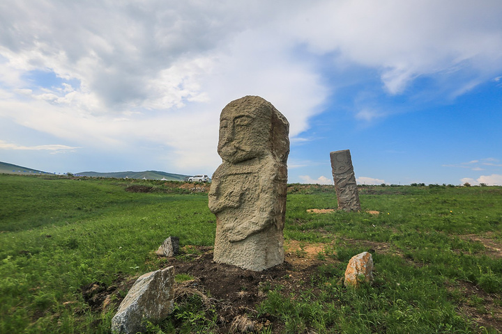 身上雕凿出翻领大袷袢,腰部束一根宽腰带,右手拿一只杯子举在胸前石人