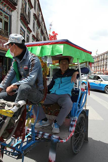 拉萨的三轮车挺有特色,小伙子车上放着佛教歌曲,按着铃铛,骑得还挺快.